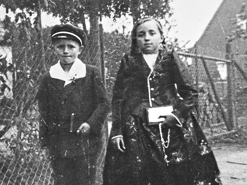 Maria Margareta Derfu&szlig; geht als Kind in ihrer Tracht zur Erstkommunion, neben ihr ihr Bruder Wendelin Derfu&szlig;.