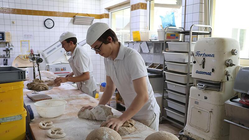 Brote oder Brezeln formen mit den H&auml;nden: Auszubildender Tim (vorne) bei der Arbeit.