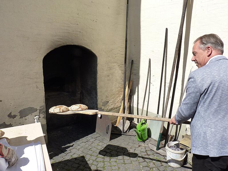 Landrat Alexander Tritthart schiebt beim Mühlentag in Lonnerstadt ein Brot in den Backofen. Landrat Alexander Tritthart schiebt beim Mühlentag in Lonnerstadt ein Brot in den Backofen.