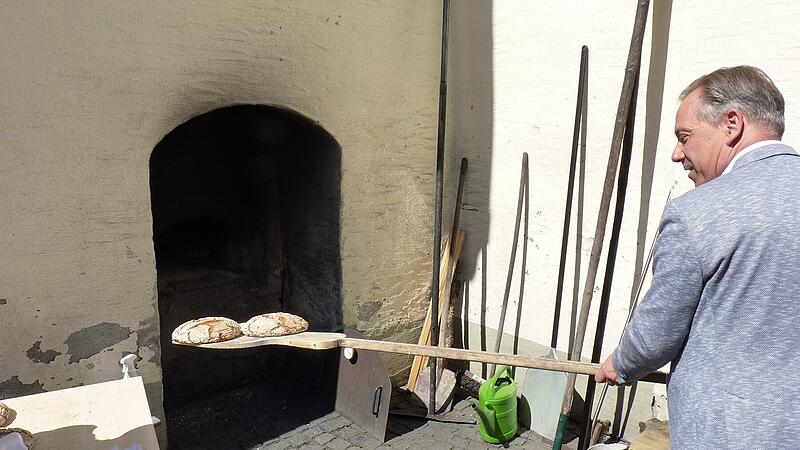 Landrat Alexander Tritthart schiebt beim Mühlentag in Lonnerstadt ein Brot in den Backofen. Landrat Alexander Tritthart schiebt beim Mühlentag in Lonnerstadt ein Brot in den Backofen.