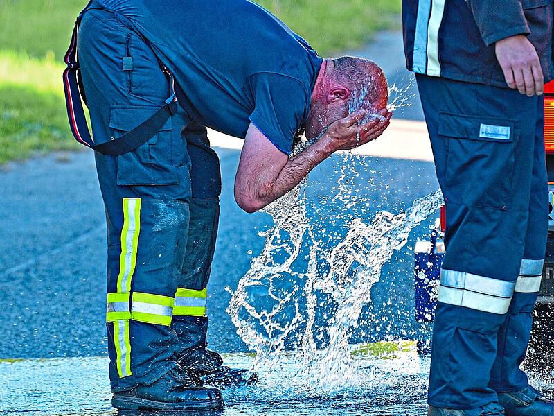 Ein Feuerwehrmann k&uuml;hlt sich bei einem Einsatz ab.SMS|Schalk, Manfred, Schrobenhausen