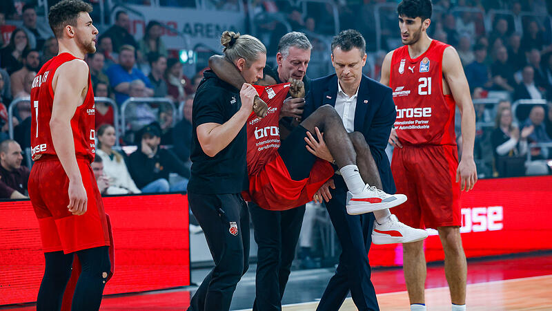 Amir Bell wird unter Tränen von Physiotherapeut Kilian Flierl,  Teamarzt Eike Schuster und Assistenztrainer Stefan Weissenböck vom Feld getragen.