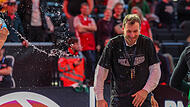 Mit einem verschmitzten L&auml;cheln versucht der Bamberger Coach Anton Gavel der Wasserdusche auf dem Parkett zu entkommen.