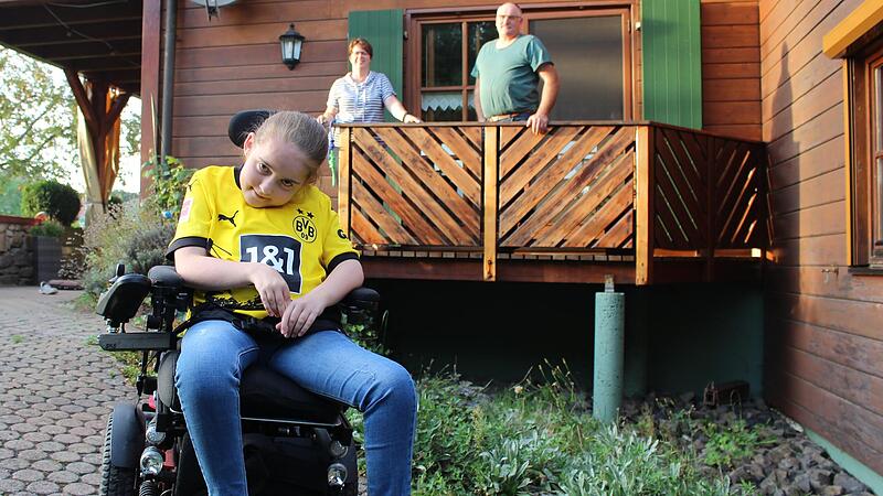 Luisa Bischof und ihre Eltern Katrin und Jürgen am Eingang zur Wohnung. Dort soll eine Rampe für den Rollstuhl gebaut werden.  Das geht aber nur mit Hilfe von Spenden.