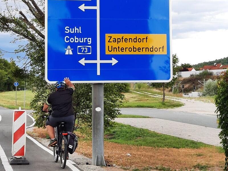 Der Rattelsdorfer Thomas Huber testet die Höhe des blauen Verkehrsschildes.