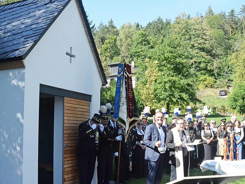 Pfarrer Hans-Michael Dinkel, assistiert von Bürgermeister Daniel Weißerth (mit Weihwasserkessel) bei der Segnung der Kapelle. Hinten rechts Vorsitzender des Knappenvereins, Heiko Eisenbeiß.