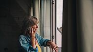 Eine Frau telefoniert am Fenster