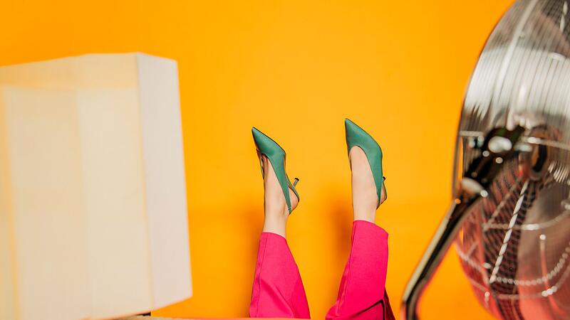 Geschäftsfrau kopfüber am Schreibtisch mit Ventilator