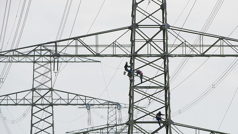 Arbeiter stehen am bei Wartungsarbeiten auf einem Freileitungsmast. Der Solarboom bringt die Netze an Grenzen. Arbeiter stehen am bei Wartungsarbeiten auf einem Freileitungsmast. Der Solarboom bringt die Netze an Grenzen.