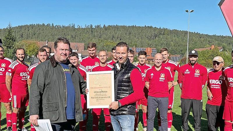 Nachtr&auml;glich zum 100. Jubil&auml;um, das der VfR Johannisthal 2020 h&auml;tte feiern k&ouml;nnen, &uuml;berbrachte der BLSV-Kreisvorsitzende Mario Schmid (vorne links) die Ehrenurkunde und gratulierte zum Jubil&auml;um. Die Ehrenurkunde nahm Vorsitzender Marc Bergauer (vorne rechts) mit Dank entgegen. Im Hintergrund die Spieler der Ersten Fu&szlig;ballmannschaft des VfR Johannisthal.