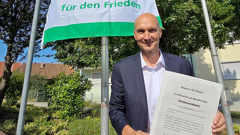 Bürgermeister Jürgen Jäkel zeigt die Mitgliedsurkunde für „Mayors for Peace“. Die Flagge der weltweiten Vereinigung von Kommunen wird künftig immer am 8. Juli, dem Flaggentag von „Mayors for Peace“ gehisst.