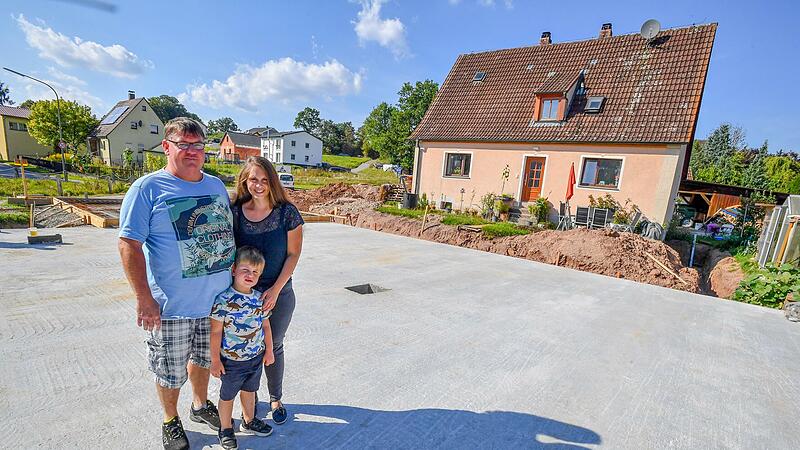 Familie Hoch auf ihrer Baustelle neben dem Elternhaus – die Bodenplatte ist fertig, jetzt warten sie darauf, dass das Holzhaus kommt. Familie Hoch auf ihrer Baustelle neben dem Elternhaus – die Bodenplatte ist fertig, jetzt warten sie darauf, dass das Holzhaus kommt.