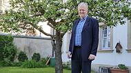 Thomas Teuchgräber steht im Pfarrhausgarten hinter der St. Johannes-Kriche.