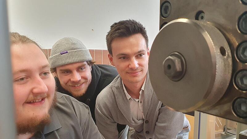 Jonas N&uuml;sslein, Felix Haberkorn und Valentin Wiesner (v.l.) aus dem neuen Studiengang Additive Manufacturing and Leightweight Design an einer Zugpr&uuml;fmaschine, mit der die Eigenschaften von Metallen untersucht werden.