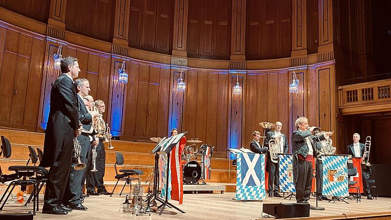 Bob Ross inmitten des Blechschaden-Ensembles im Bad Kissinger Regentenbau: Die Musiker lieferten ein mitrei&szlig;endes Konzert an Neujahr.