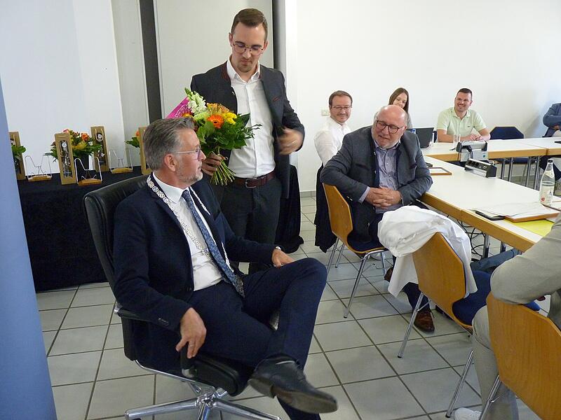 Nico Kauper (stehend) beerbt Karsten Fischkal (sitzend) zwar um dessen B&uuml;rgermeisterposten, nicht jedoch um dessen Sessel. Diesen erh&auml;lt der scheidende B&uuml;rgermeister als Geschenk.