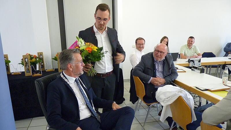 Nico Kauper (stehend) beerbt Karsten Fischkal (sitzend) zwar um dessen B&uuml;rgermeisterposten, nicht jedoch um dessen Sessel. Diesen erh&auml;lt der scheidende B&uuml;rgermeister als Geschenk.