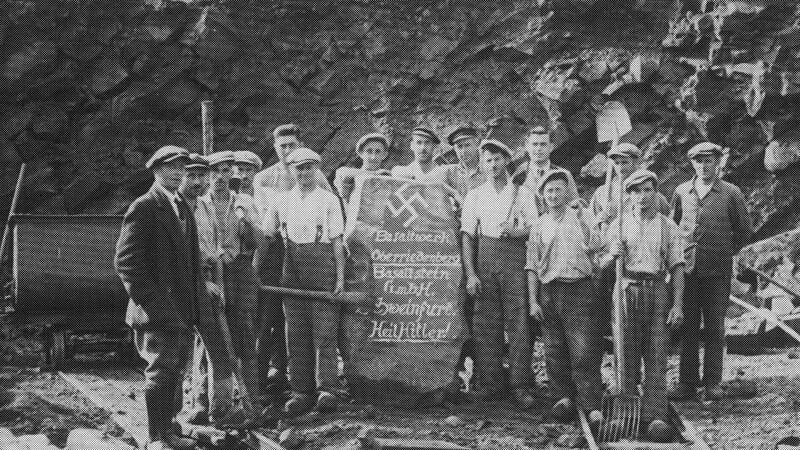 1935 hatte Hitler viele Anh&auml;nger in Deutschland. Auch in der Rh&ouml;n: Im Basaltwerk posieren Arbeiter rund um einen Gedenkstein, etwa um 1935 herum. Auf dem Stein ist ein Hakenkreuz zu sehen, darunter steht "Basaltwerk Oberriedenberg Basaltstein GmbH Schweinfurt Heil Hitler!"