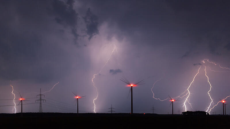 Blitze erleuchten den Himmel zwischen Windrädern Blitze erleuchten den Himmel zwischen Windrädern