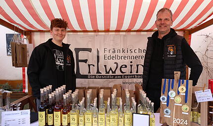Matthias Erlwein und sein Sohn Jona stehen  am Stand mit ausgew&auml;hlten Brenn-Spezialit&auml;ten aus Weigelshofen.