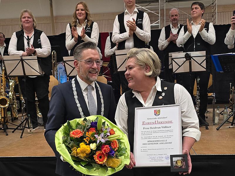 B&uuml;rgermeister Karsten Fischkal &uuml;berreichte Heidrun V&ouml;llner Urkunde und Medaille. Die Musikanten applaudieren.&ensp;