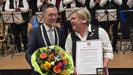 B&uuml;rgermeister Karsten Fischkal &uuml;berreichte Heidrun V&ouml;llner Urkunde und Medaille. Die Musikanten applaudieren.&ensp;