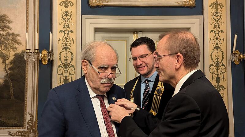 Zweiter Bürgermeister Hans-Herbert Hartan (rechts) hat Gert Melville (links) die Anstecknadel zur Bürgermedaille ans Sakko platziert.