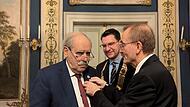 Zweiter Bürgermeister Hans-Herbert Hartan (rechts) hat Gert Melville (links) die Anstecknadel zur Bürgermedaille ans Sakko platziert.
