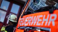 Feuerwehrmann steht neben einem Feuerwehrauto (Symbolbild)