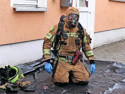 Ersch&ouml;pft nach dem Innenangriff: Ein Atemschutzger&auml;tetr&auml;ger der Feuerwehr kniet nach seinem Einsatz vor dem Geb&auml;ude.
