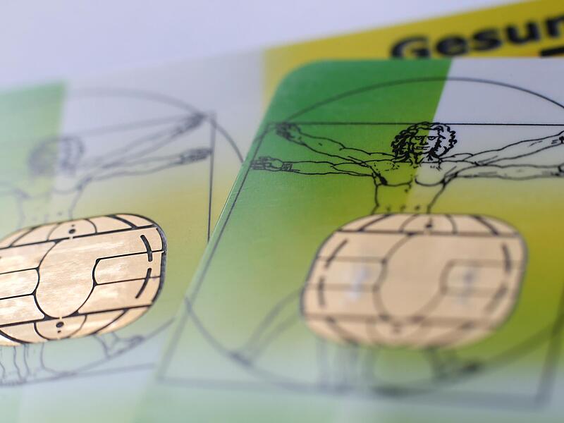 Zwei elektronische Versichertenkarten  liegen auf einem Tisch.