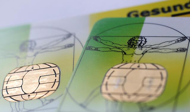 Zwei elektronische Versichertenkarten  liegen auf einem Tisch.