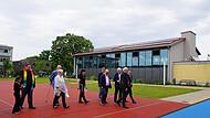 Die Ehrengäste unterwegs bei der Segnung. Im Hintergrund die sanierte Turnhalle.