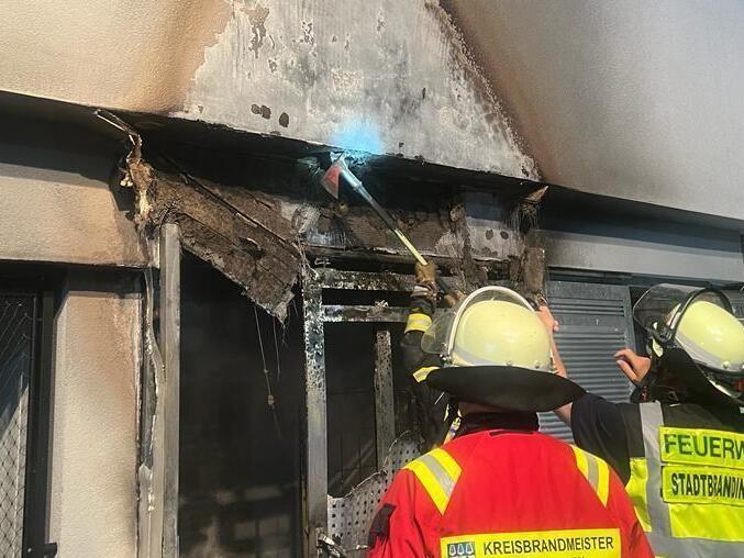 Feuerwehrleute inspizieren die beschädigte Fassade. Feuerwehrleute inspizieren die beschädigte Fassade.