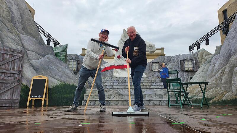 Volker Hei&szlig;mann (links) und Martin Rassau lassen sich auch vom Regen nicht die Laune verderben. Die Hauptdarsteller packen bei den Proben im Luitpoldbad in Bad Kissingen mit an und schieben die  Flut von der B&uuml;hne.