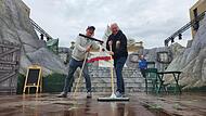Volker Hei&szlig;mann (links) und Martin Rassau lassen sich auch vom Regen nicht die Laune verderben. Die Hauptdarsteller packen bei den Proben im Luitpoldbad in Bad Kissingen mit an und schieben die  Flut von der B&uuml;hne.