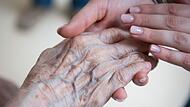 Pflegerin hält Hand einer Seniorenheim-Bewohnerin Pflegerin hält Hand einer Seniorenheim-Bewohnerin