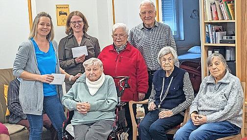Norbert Lawatsch (hinten, r.), Elisabeth Ramming (Strickkreis, links daneben) Diana Pausch (Sozialstation, links daneben), Eva Seibold (Tagespflege, links daneben) sowie im Vordergrund G&auml;ste der Tagespflege bei der Spenden&uuml;bergabe.
