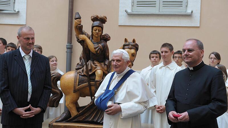 Der H&ouml;chstadter B&uuml;rgermeister Gerald Brehm (li.) und Dekan Kemmer (re.) &uuml;bergeben im Jahr 2009 mit den H&ouml;chstadter Ministranten die 300 Kilo schwere Figur vom Hl. Georg an Papst Benedikt XVI. (Mitte).