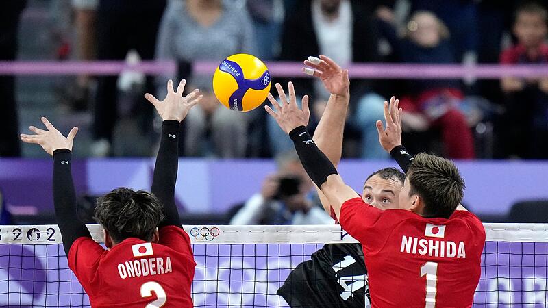 Der Hammelburger Moritz Karlitzek (schwarzes Trikot) schlägt den Ball gegen Japans Taishi Onodera (links) und Yuji Nishida.