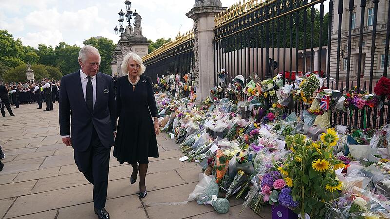 K&ouml;nig Charles III. und seine Frau Camilla sehen sich die Blumengestecke und pers&ouml;nlichen Gru&szlig;worte an, die nach dem Tod von K&ouml;nigin Elizabeth II. vor dem Buckingham-Palast abgelegt wurden.