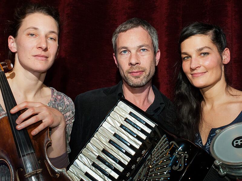 Seit 2007 spielen Friederike Oertel-Benchouchou (Geige) und &bdquo;Max&ldquo; Marcus Stadler (Akkordeon) als Kern der Weltmusikcombo TRIGANE zusammen, seit 2012 mit Timea Teleki als Percussionistin.