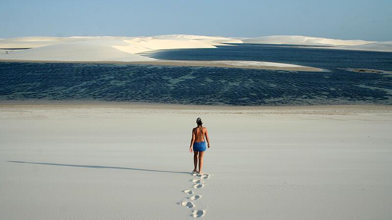 Frau läuft durch Dünenlandschaft zu einer kleinen Lagune Frau läuft durch Dünenlandschaft zu einer kleinen Lagune
