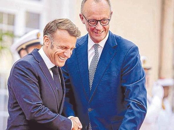 Wie zwei alte Freunde begrüßen sich Emmanuel Macron und Friedrich Merz.