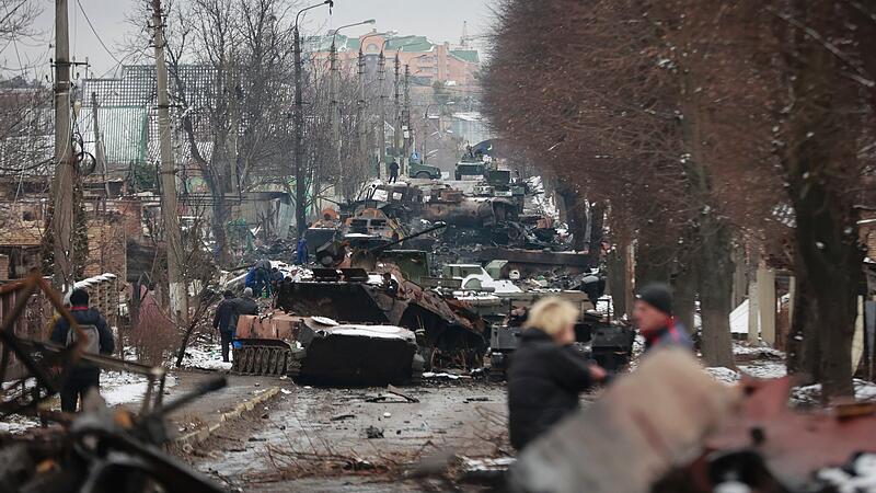 Menschen betrachten die ausgebrannten &Uuml;berreste russischer Milit&auml;rfahrzeuge auf einer Stra&szlig;e in der Stadt Bucha in der N&auml;he der ukrainischen Hauptstadt Kiew.