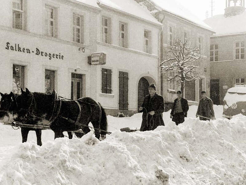 Winterimpression 1956: Mit einem Haflinger-Gespann wird die die Marktstraße von meterhohem Schnee geräumt.