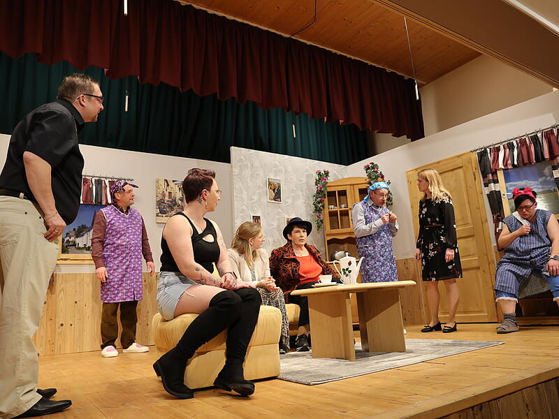 Alle vereint: Die M&auml;nner vom Club der Pantoffelhelden, Richie Naumann (Julian Hildner&ldquo;, die verruchte Barfrau Carmen (Marina G&ouml;ppner), die Ehefrauen und Hausmeisterin Christine Zausel (Nicole Kratkai).