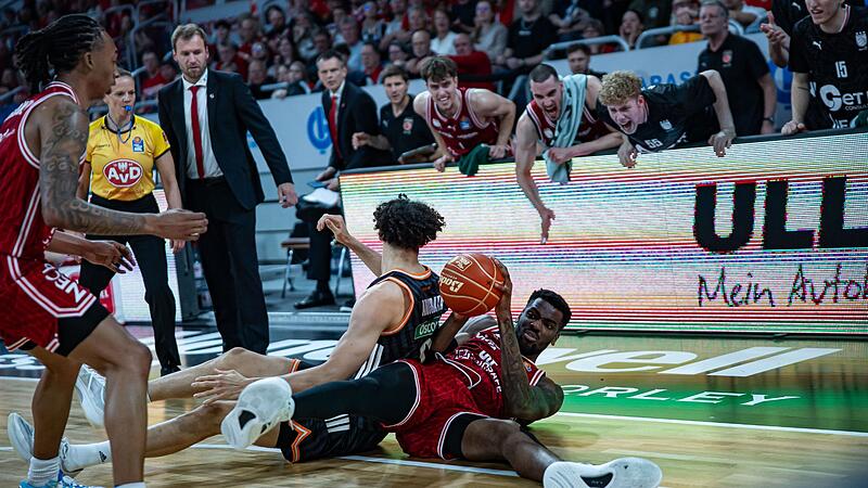 Baskets-Center EJ Onu erkämpft sich das Spielgerät im Bodenkampf gegen den Ulmer Alec Anigbata und wird von seinen Teamkollegen euphorisch angefeuert. Baskets-Center EJ Onu erkämpft sich das Spielgerät im Bodenkampf gegen den Ulmer Alec Anigbata und wird von seinen Teamkollegen euphorisch angefeuert.