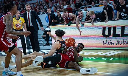 Baskets-Center EJ Onu erkämpft sich das Spielgerät im Bodenkampf gegen den Ulmer Alec Anigbata und wird von seinen Teamkollegen euphorisch angefeuert. Baskets-Center EJ Onu erkämpft sich das Spielgerät im Bodenkampf gegen den Ulmer Alec Anigbata und wird von seinen Teamkollegen euphorisch angefeuert.