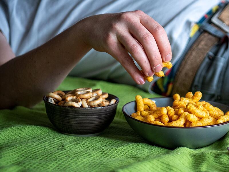 Mann isst auf einem Sofa Chips